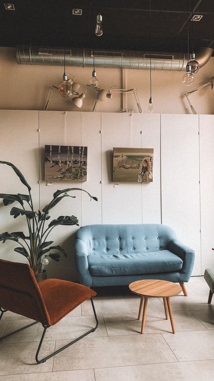 Chic modern lounge featuring a blue sofa, stylish chairs, and wall art.